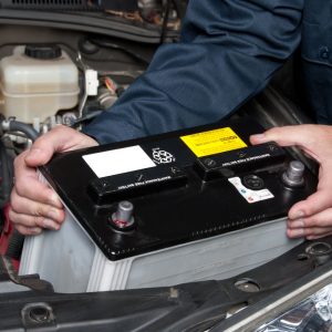 A mobile mechanic exchanges a car battery.