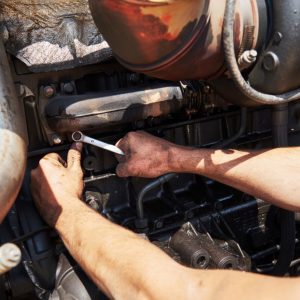 A mobile mechanic repairs a transmission.